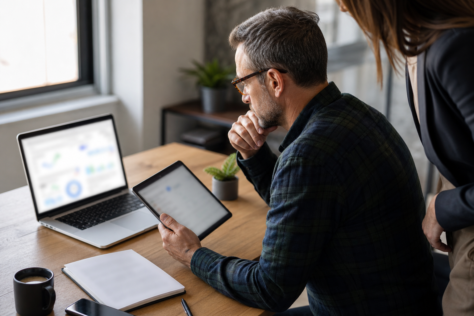 Small business owner comparing blurred AI search signals on a laptop and tablet